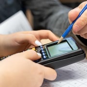 Un professeur explique le problème mathématique à une élève sur une calculatrice scientifique.