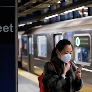Une femme porte un masque dans le métro de New York.