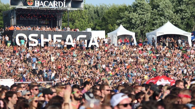 Une foule immense et compacte devant une scène au festival Osheaga.