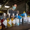 Une femme portant un masque aligne des bouteilles de désinfectant avec des bouteilles de rhum sur un comptoir.