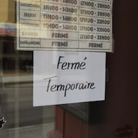 Une affiche de fermeture dans la porte d'un commerce.