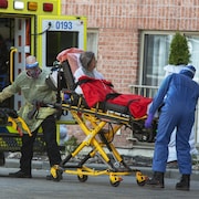 Une résidente d'un foyer pour personnes âgées de l'ouest de Montréal est transportée par des ambulanciers.