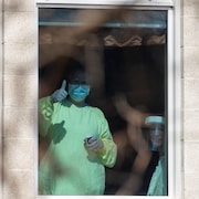 Des travailleurs de la santé sont derrière une fenêtre, dans un CHSLD.