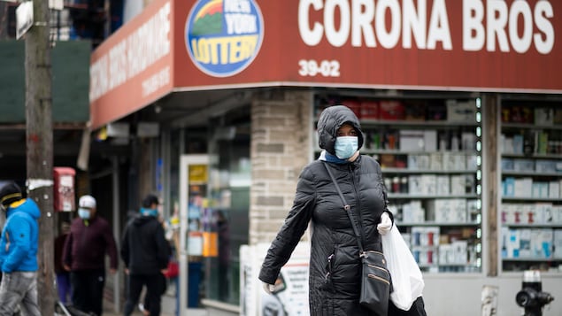 Des New-Yorkais portant le masque marchent dans la rue.