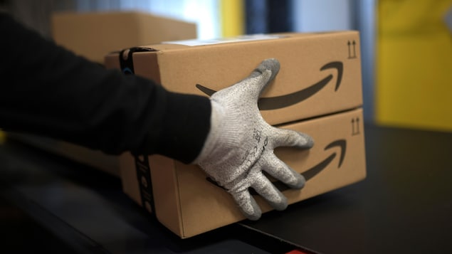 Un employé tient des colis dans un centre de distribution d’Amazon.