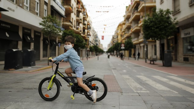 Un enfant à vélo traverse une rue. 