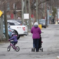Une femme se promène avec de jeunes enfants dans une ruelle de Montréal.