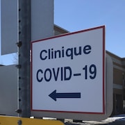Une affiche indique la direction à prendre pour se rendre dans une clinique dédiée au dépistage de la COVID-19.