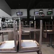 Des chaises retournées sur des tables dans un restaurant fermé.