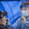 Une professionnelle de la santé effectue un test de dépistage de la COVID-19 sur un patient en lui insérant un écouvillon dans le nez.