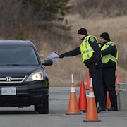 Un agent portant une veste jaune remet un document à quelqu'un dans sa voiture.