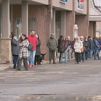 Plusieurs dizaines de personnes font la file pour entrer dans un magasin de tissu.