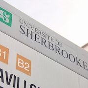 Une pancarte de l'Université de Sherbrooke située devant un pavillon.