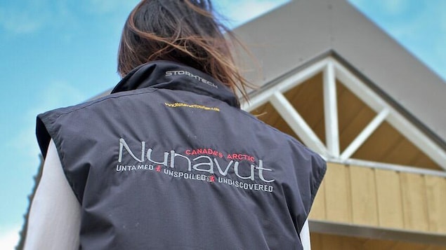 Un employé portant une tenue avec le logo d'un organisme de tourisme du Nunavut.