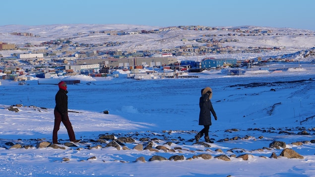 Deux personnes marchent dehors dans la toundra, près de la ville d'Iqaluit, au Nunavut.