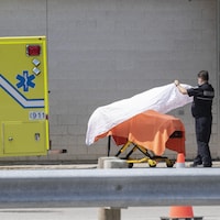 Un ambulancier dépose un drap blanc sur une civière.