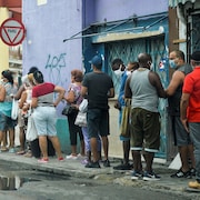 Une dizaine de personnes sont sur un trottoir de la capitale cubaine.