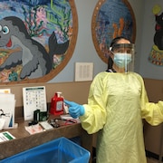 Une médecin de famille dans une clinique avec un équipement complet de protection.