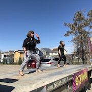 Deux jeunes femmes dansent avec entrain sur une scène extérieure.