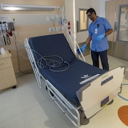 Un préposé aux bénéficiaires désinfecte un lit d'hôpital.