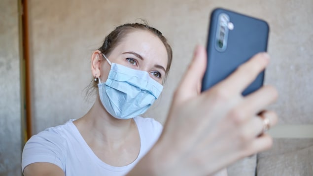 Une femme portant un masque hygiénique prend un égoportrait.