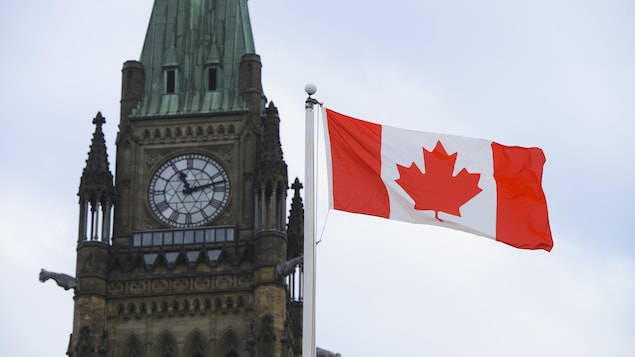Un drapeau flotte devant le parlement à Ottawa. 