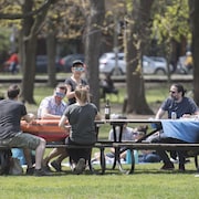 Six personnes sont assises à des tables à pique-nique, à distance réglementaire en temps de pandémie, dans un parc de Montréal.