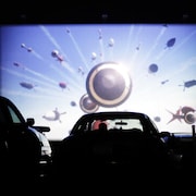 Une personne regarde un film dans sa voiture dans un ciné-parc.