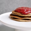 Quatre pancakes sur un plat de service servi avec de la compote.