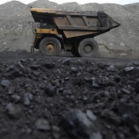 Un camion roule sur une terre noircie par le charbon