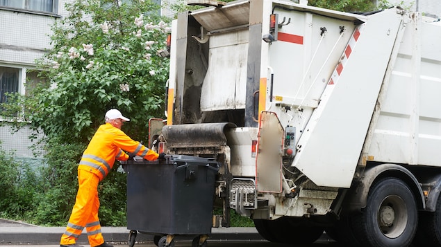 Un travailleur met des déchets dans le camion à ordures