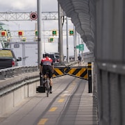 Un jeune homme à vélo arrive devant des barrières de ralentissement sur la piste cyclable du pont Jacques-Cartier.