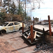 Les ruines calcinées d'un chalet et la carcasse d'une voiture incendiée.