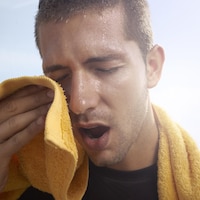 L'homme essuie son visage avec une serviette.