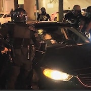 Plusieurs agents tentent de sortir d'un véhicule un jeune Afro-Américain.