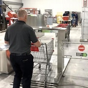 Un homme pousse un panier d'épicerie dans le robot désinfectant. 