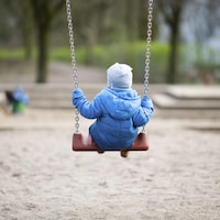 Un jeune enfant se balance dans un parc.
