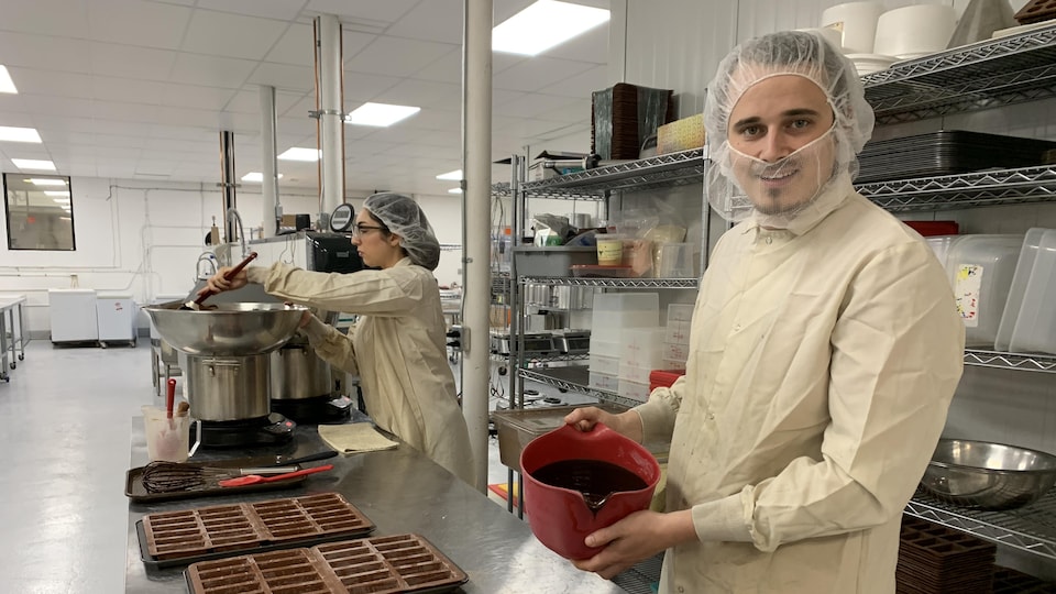 Un homme prépare du chocolat dans une cuisine professionnelle.
