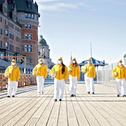 Des membres de l'Église de Scientologie qui portent des manteaux jaunes et des masques sur la terrasse Dufferin à Québec.