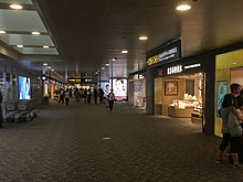 In this image, you can see shops and a bathroom sign located in a hallway in Terminal 2.