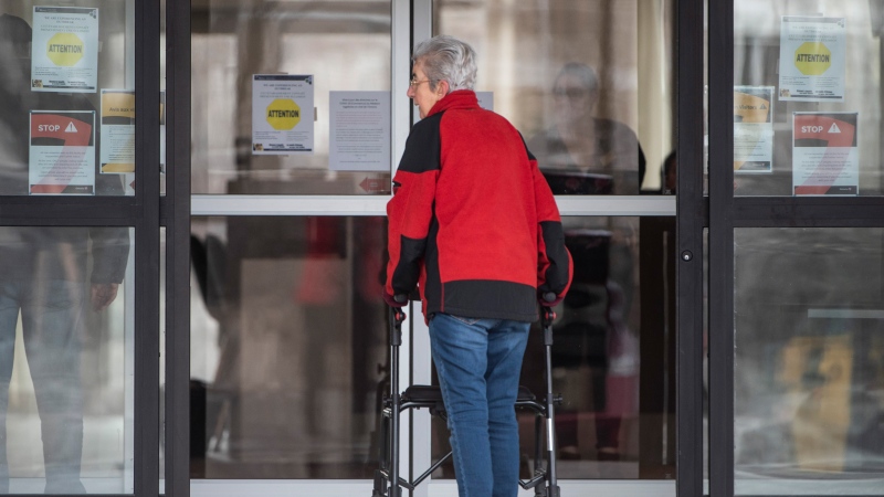 A person re-enters a building at the Promenade retirement residence, where local health officials reported Ottawa's first case of COVID-19 in a retirement or long-term care home after a resident tested positive for the novel coronavirus, on Saturday, March 28, 2020. THE CANADIAN PRESS/Justin Tang