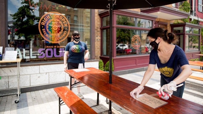 Owner Leah Cheston, right, and Assistant General Manager Tylyn Mallon, left, set up the outdoor patio at Right Proper Brewing Company in the Shaw neighborhood in Washington, Friday, May 29, 2020, after the District of Columbia gradually loosens stay-at-home rules that have been in place since March 25 because of the pandemic and allows restaurants to resume outdoor dining. (AP Photo/Andrew Harnik)