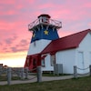Un phare décoré aux couleurs acadiennes au coucher du soleil.
