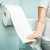 Une femme aux toilettes tient un rouleau de papier à la main. 