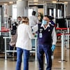Un employé de l'aéroport portant un masque aide une femme qui porte elle-aussi un masque.