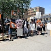Une douzaine de manifestants brandissent des affichent où on lire des slogans interpellant le premier ministre du Québec.