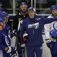 Un entraîneur de hockey donne des directives durant un entraînement.