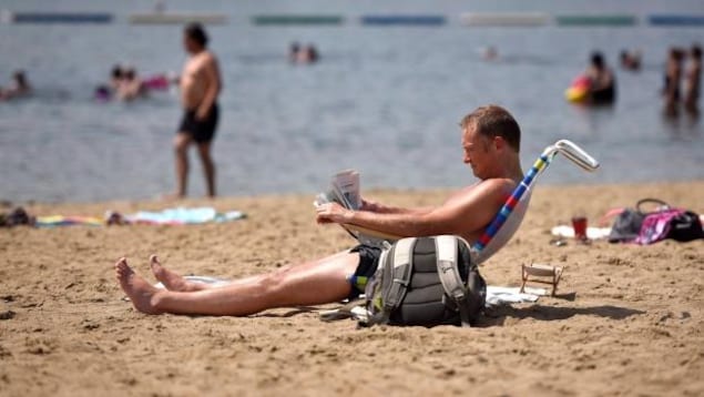 Un homme assis sur une chaise de plage, à la plage de Mooney's Bay à Ottawa.