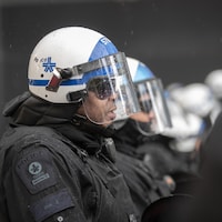 Des policiers côte à côte portant leur casque avec visière.