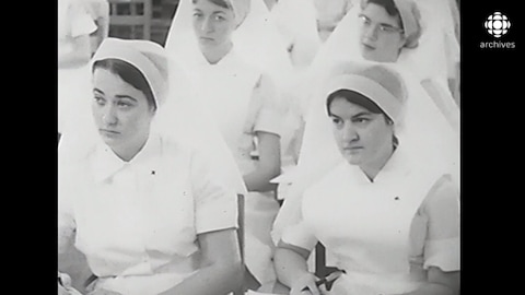 De jeunes femmes qui portent l'uniforme (robe et coiffe) sont assises dans une classe.